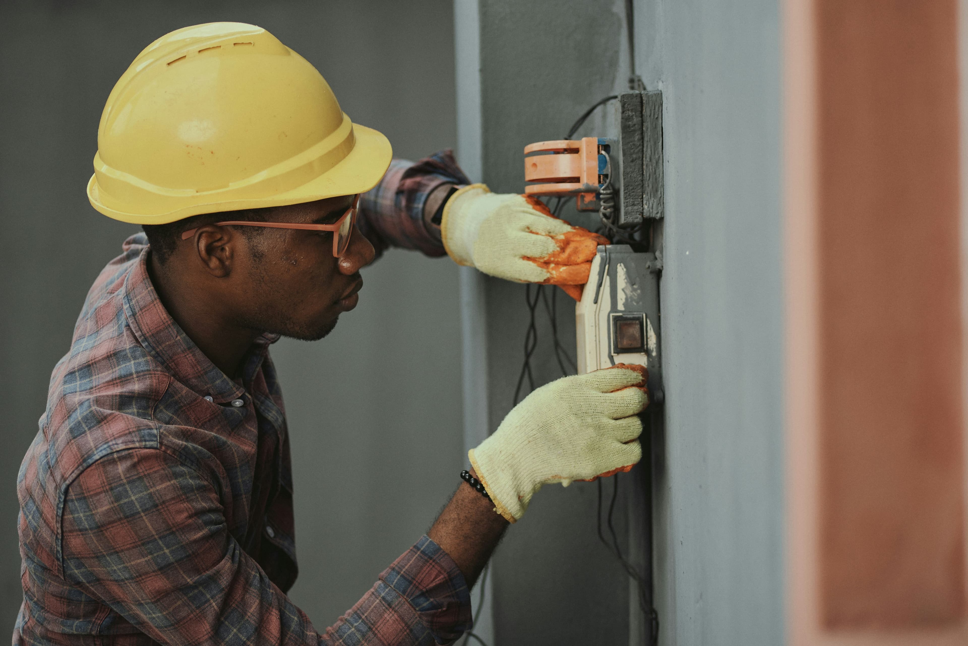 Technicien en casque de chantier intervenant sur un tableau électrique